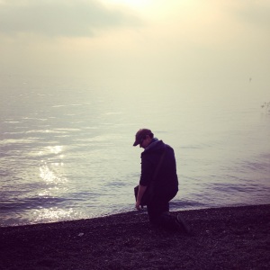 Justin kneeling by the Sea of Galilee on New Year's Day